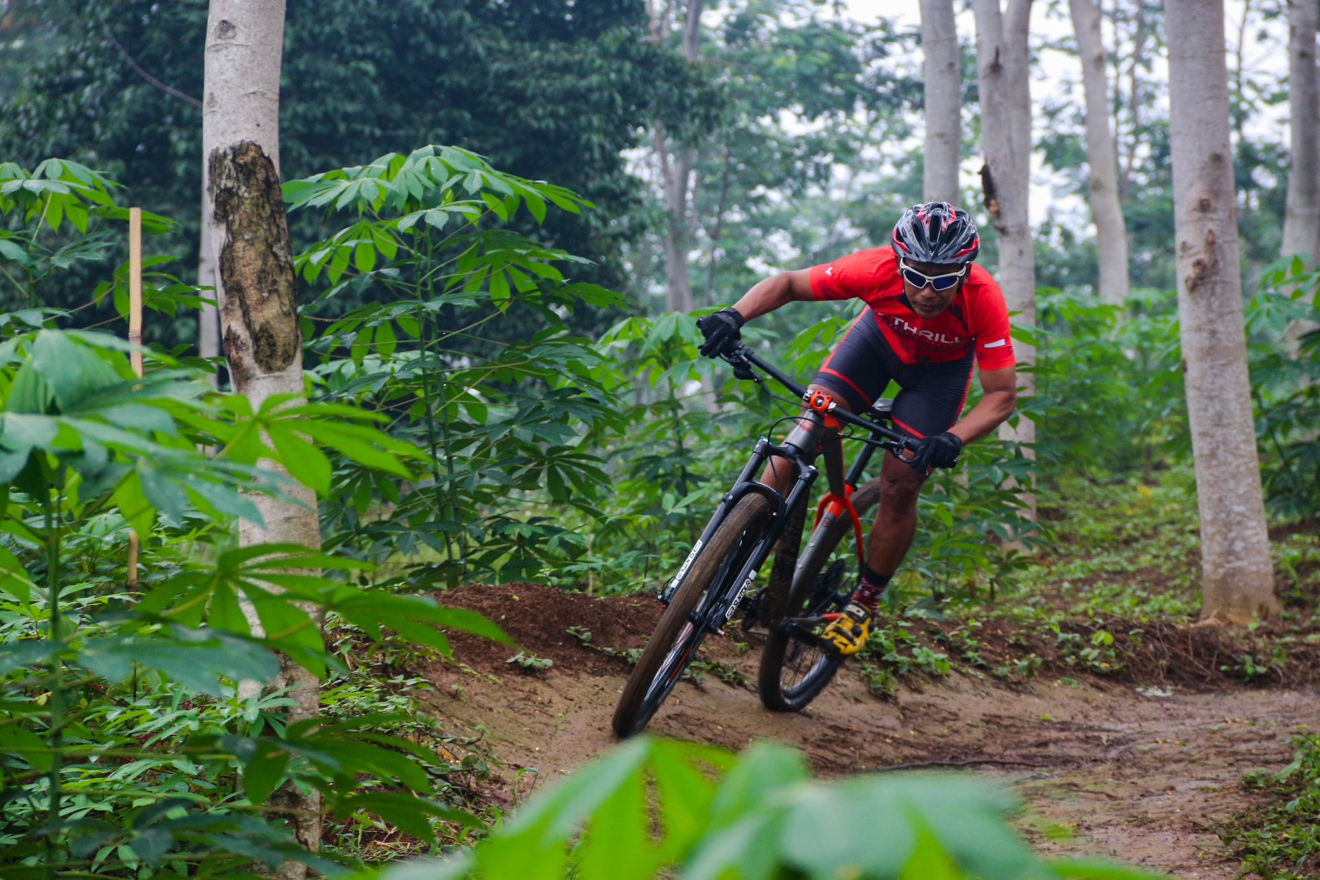 Thrill mountain biker leaning into a sharp turn on a wooded dirt trail